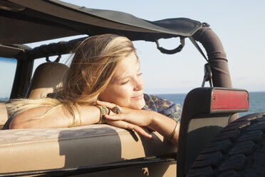 Junge Frau lehnt sich an ein Jeepfenster an der Küste, Malibu, Kalifornien, USA - ISF16959