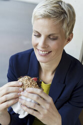 Smiling woman eating sandwich - CUF39654