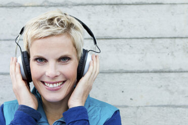 Smiling woman listening to headphones - CUF39667