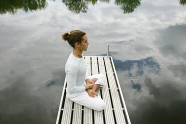 Man meditating on wooden pier - CUF39689