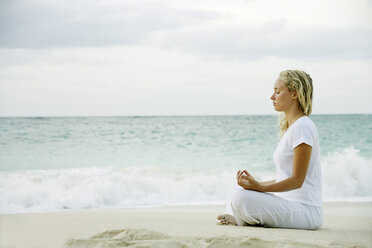 Woman meditating on tropical beach - CUF39693