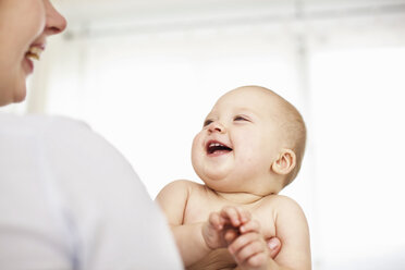 Mother holding laughing baby girl - CUF39744