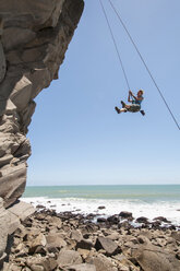 Rock climber abseiling jagged cliff - CUF39763