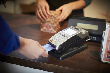 Cropped image of customer paying through credit card at checkout counter - MASF08037