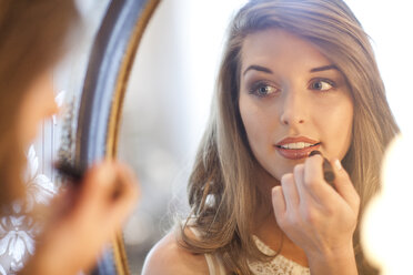Young woman applying lipstick in mirror - CUF39780