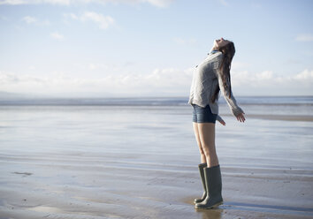 Junge Frau steht am Strand und schaut nach oben, Brean Sands, Somerset, England - CUF39873