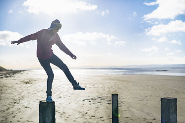 Young man standing on groynes, Brean Sands, Somerset, England - CUF39875