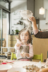 Mother and daughter sieving flour in kitchen - CUF39913