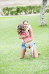 Mother and daughter hugging on lawn - CUF39923