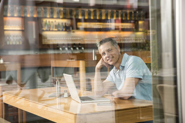 Geschäftsmann mit Laptop, Blick durch ein Fenster - CUF39948