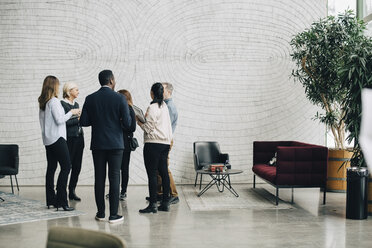 Business people discussing while standing in meeting at office - MASF08057