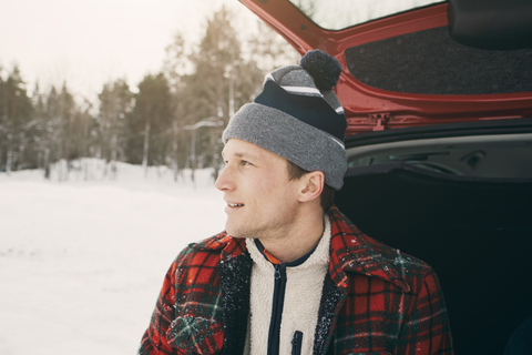 Close-up of thoughtful man looking away while sitting in car trunk stock photo