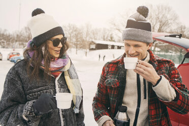 Smiling friends talking while having coffee at snowy park - MASF08113