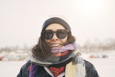 Nahaufnahme einer lächelnden Frau mit Schal und Sonnenbrille in einem Park im Winter - MASF08118