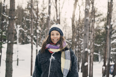 Portrait of smiling mid adult woman standing against bare trees during winter - MASF08145