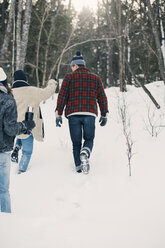 Rear view of friends walking on snow covered field - MASF08156