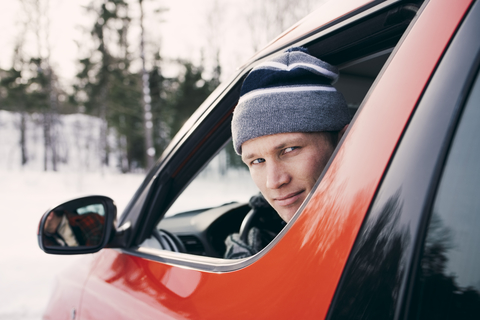 Porträt eines mittleren erwachsenen Mannes in einem roten Auto sitzend, lizenzfreies Stockfoto
