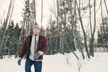 Portrait of mid adult man walking against trees on snow covered landscape - MASF08159