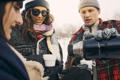 Man serving coffee to friend from insulated drink container - MASF08166