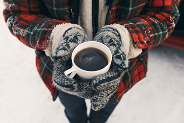 Mittelteil eines Mannes, der eine Kaffeetasse hält, während er auf Schnee steht - MASF08168