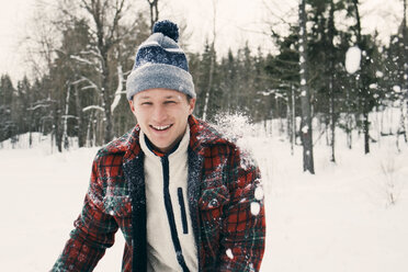 Porträt eines glücklichen erwachsenen Mannes in warmer Kleidung auf einem schneebedeckten Feld - MASF08173