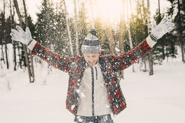 Happy mid adult man playing with snow on snow covered field - MASF08176