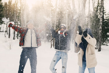 Playful friends throwing snow while standing on field at park - MASF08177