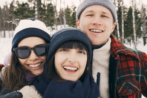 Portrait of cheerful friends wearing knit hats at park during winter - MASF08181