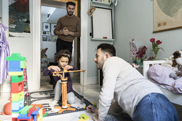 Fathers looking at girl playing with crane toy at home - MASF08196