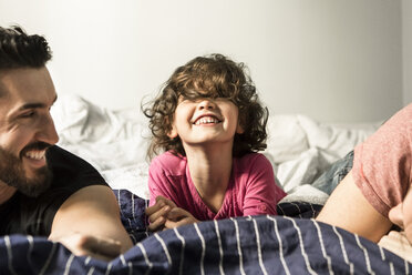 Fathers looking at cheerful daughter playing on bed at home - MASF08205