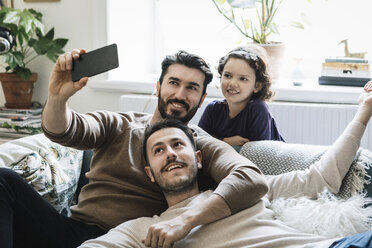 Fathers and daughter taking selfie through mobile phone in living room at home - MASF08218