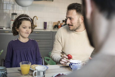 Vater sieht seine Tochter beim Frühstück in der Küche an - MASF08227