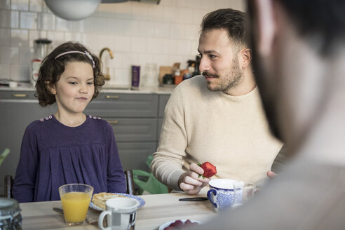 Vater sieht seine Tochter beim Frühstück in der Küche an - MASF08227