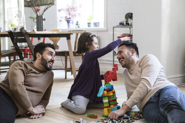 Cheerful fathers and daughter playing with toy blocks at home - MASF08240