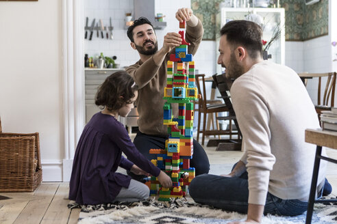 Happy gay men playing blocks with daughter at home - MASF08242