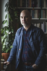 Portrait of confident mature therapist standing by potted plant at home office - MASF08245