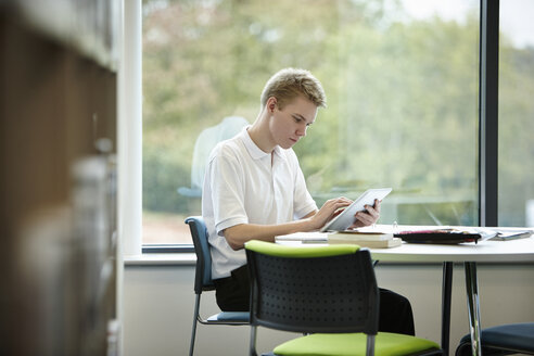 Jugendlicher benutzt digitales Tablet in der Bibliothek - CUF40076