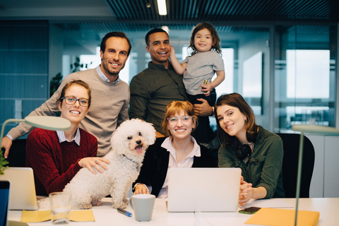 Porträt eines lächelnden Geschäftsteams mit Kind und Hund im Kreativbüro, lizenzfreies Stockfoto