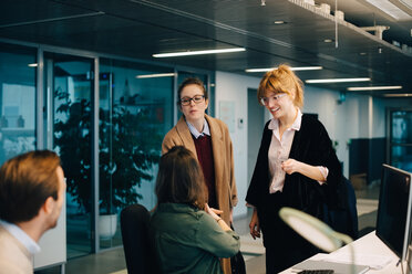 Businessman looking at smiling female colleagues greeting at creative office - MASF08262