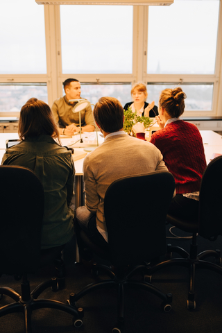Multi-ethnische Geschäftsleute sitzen am Schreibtisch und diskutieren im Sitzungssaal, lizenzfreies Stockfoto