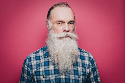 Porträt eines ernsten älteren Mannes mit langem weißen Bart vor rosa Hintergrund - MASF08320