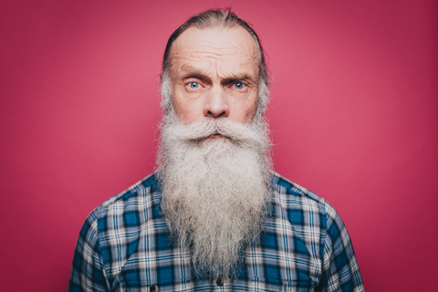 Porträt eines selbstbewussten älteren Mannes mit langem weißen Bart auf rosa Hintergrund, lizenzfreies Stockfoto