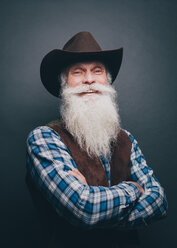 Porträt eines glücklichen älteren Mannes mit Cowboyhut vor grauem Hintergrund - MASF08322
