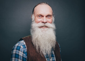 Porträt eines lächelnden älteren Mannes mit weißem Bart und Schnurrbart vor grauem Hintergrund - MASF08323
