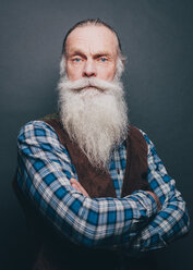 Porträt eines selbstbewussten, bärtigen älteren Mannes, der mit verschränkten Armen vor einem grauen Hintergrund steht - MASF08325