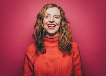 Portrait of smiling woman in orange top against pink background - MASF08335