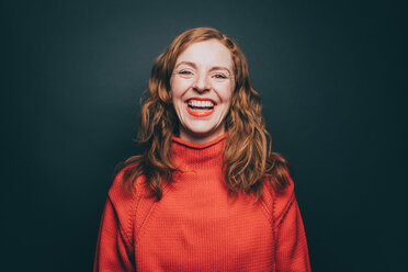 Porträt einer Frau in orangefarbenem Top, die vor grauem Hintergrund lacht - MASF08336