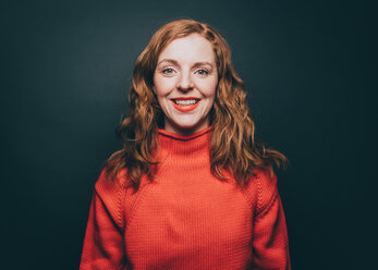 Portrait of smiling woman in orange top against gray background - MASF08337