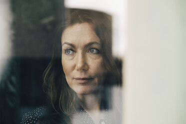 Close-up of mature businesswoman seen through window while looking away - MASF08346