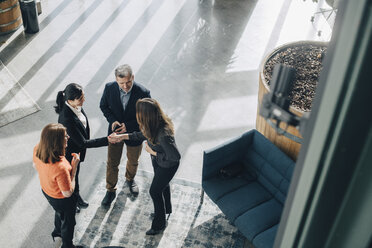 High angle view of colleagues looking at businesswomen greeting in office - MASF08355